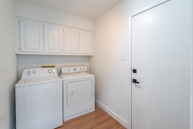 clothes washing area featuring cabinets, separate washer and dryer, and light wood-type flooring