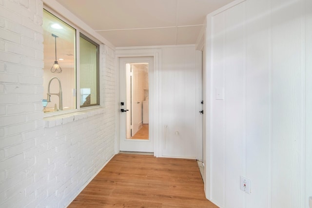 hallway featuring brick wall and light wood-type flooring