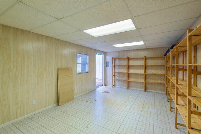 unfurnished room with a paneled ceiling and wooden walls