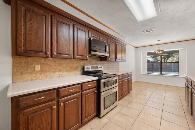 kitchen with decorative backsplash, hanging light fixtures, ornamental molding, light tile patterned floors, and stainless steel appliances