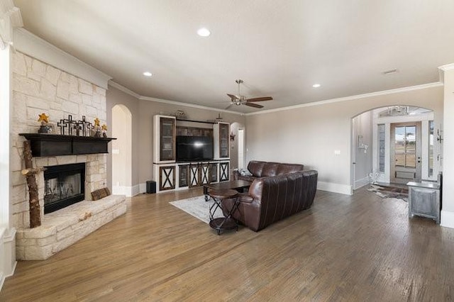 living room with wood-type flooring, a fireplace, ornamental molding, and ceiling fan