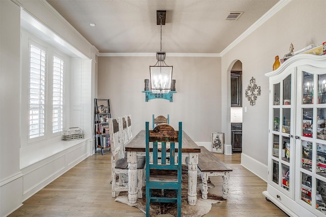 dining room with arched walkways, wood finished floors, visible vents, and crown molding