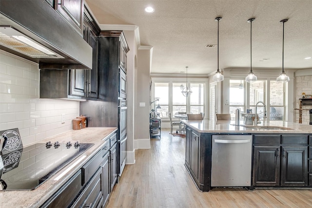 kitchen featuring stainless steel appliances, premium range hood, a sink, and decorative light fixtures