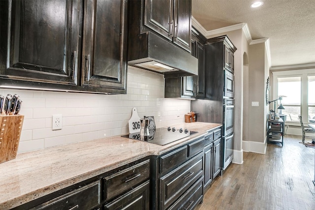 kitchen featuring baseboards, light wood-style flooring, appliances with stainless steel finishes, ornamental molding, and under cabinet range hood