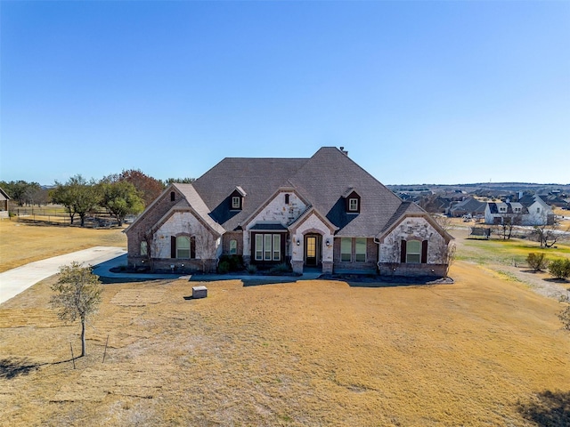 french provincial home featuring a front yard and stone siding