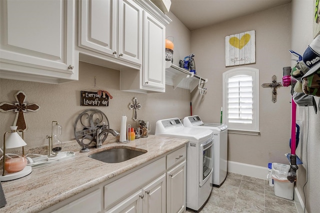 clothes washing area featuring cabinet space, light tile patterned floors, baseboards, washer and clothes dryer, and a sink