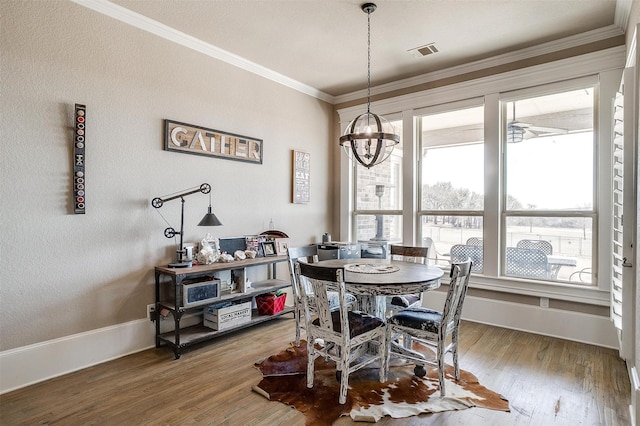 dining space with baseboards, visible vents, wood finished floors, and ornamental molding