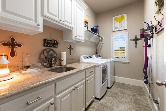 clothes washing area featuring washing machine and dryer, cabinets, and sink