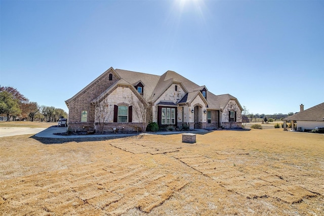 french country style house with stone siding and a front yard