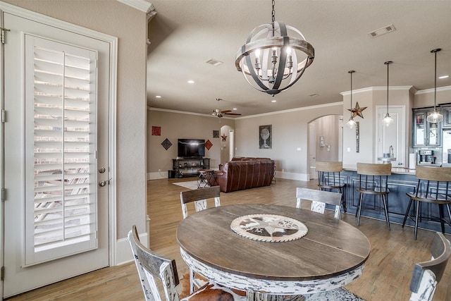 dining area with visible vents, arched walkways, ornamental molding, light wood-type flooring, and ceiling fan with notable chandelier