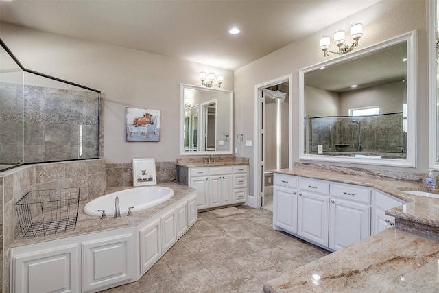 full bath featuring a stall shower, a garden tub, two vanities, and a sink