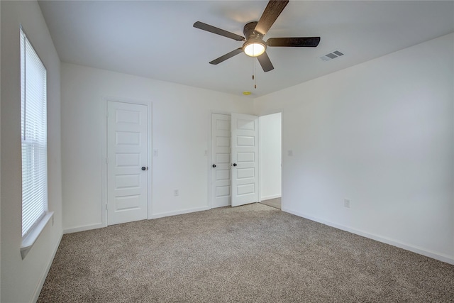 unfurnished bedroom with multiple windows, ceiling fan, and light colored carpet