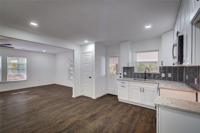 kitchen with dark hardwood / wood-style flooring, light stone counters, white cabinetry, and sink