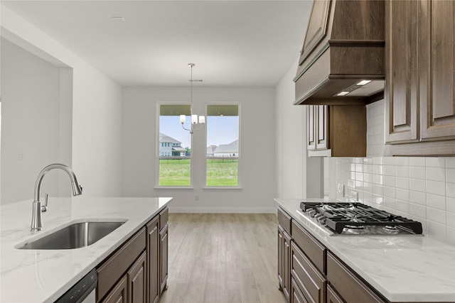 5009 Tamarack Ln, Royse City, TX 75189 - kitchen with stainless steel gas stovetop, premium range hood, a sink, light wood-style floors, and decorative backsplash