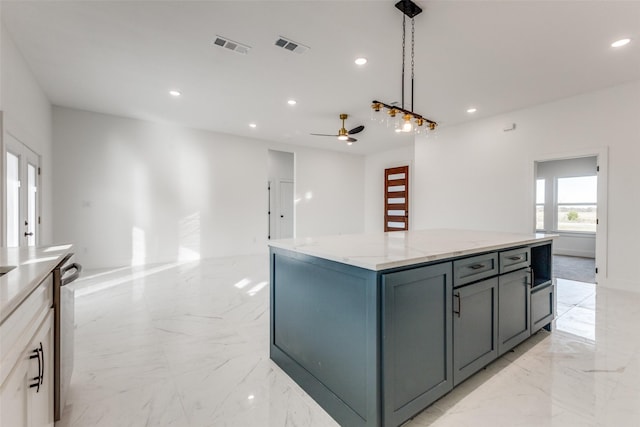 kitchen with ceiling fan, a kitchen island, light stone counters, and decorative light fixtures