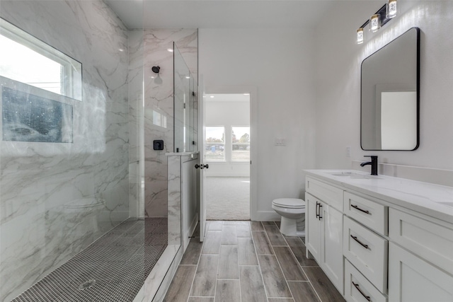 bathroom with tiled shower, a healthy amount of sunlight, and toilet