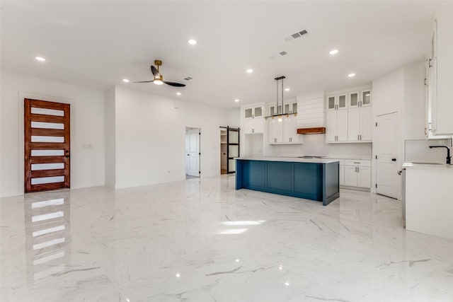 kitchen with ceiling fan, a center island, hanging light fixtures, premium range hood, and white cabinets