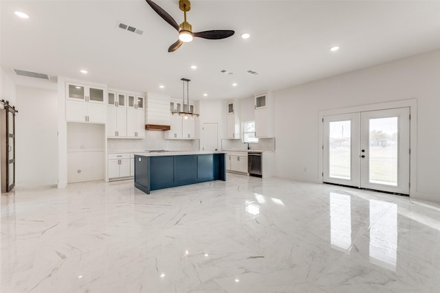 kitchen with premium range hood, a kitchen island, white cabinets, hanging light fixtures, and ceiling fan