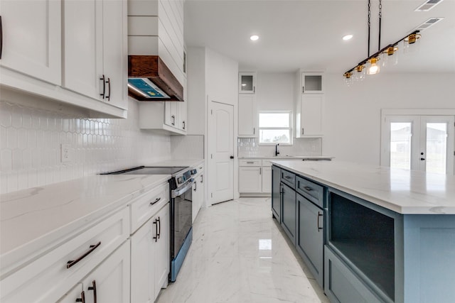 kitchen featuring tasteful backsplash, light stone counters, stainless steel electric stove, decorative light fixtures, and white cabinets