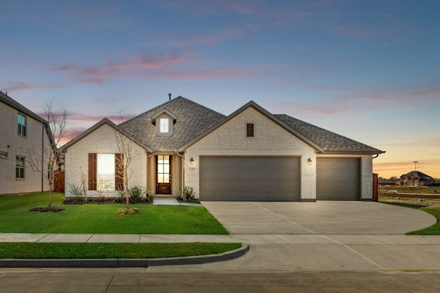 french country inspired facade featuring a yard and a garage