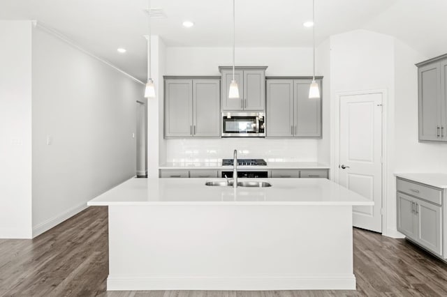 kitchen with hanging light fixtures, dark hardwood / wood-style flooring, an island with sink, and gray cabinets