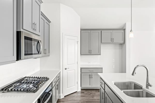 kitchen featuring pendant lighting, decorative backsplash, sink, dark wood-type flooring, and appliances with stainless steel finishes