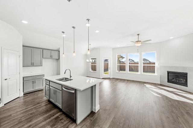 kitchen with dishwasher, an island with sink, sink, gray cabinets, and ceiling fan