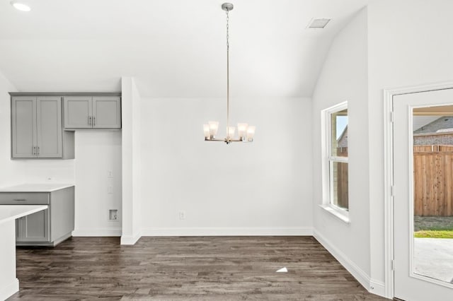 unfurnished dining area with vaulted ceiling, dark wood-type flooring, and an inviting chandelier