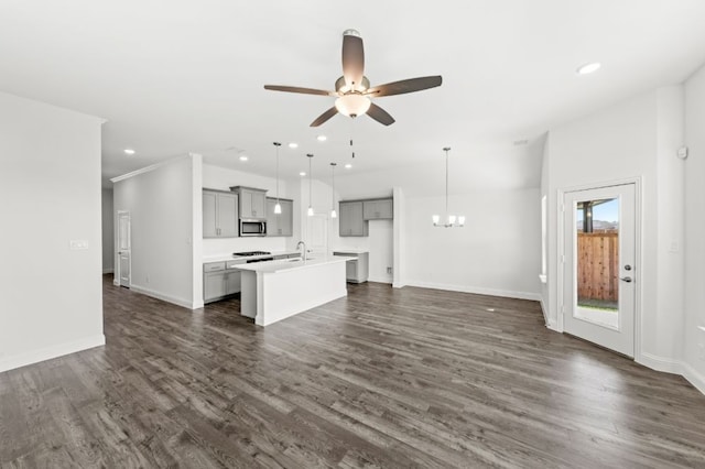 unfurnished living room with ceiling fan with notable chandelier, sink, and dark hardwood / wood-style flooring