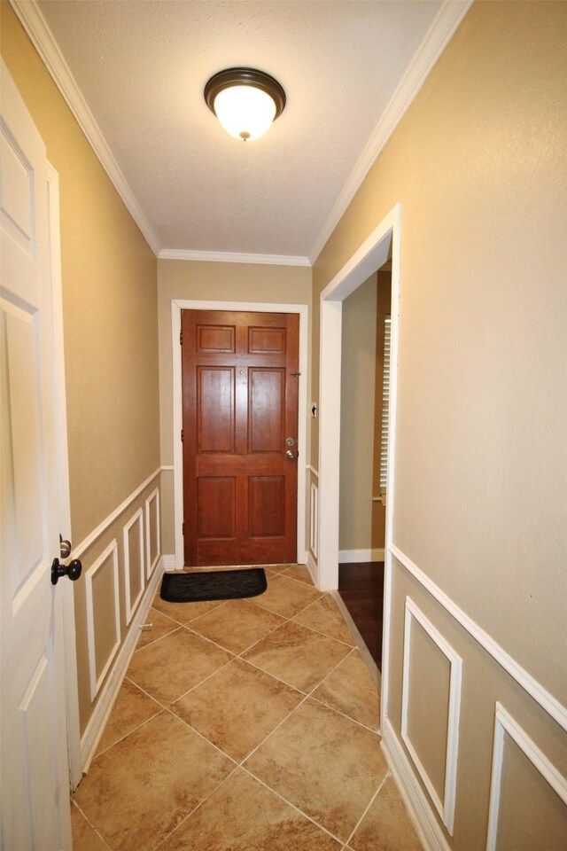 doorway with light tile patterned floors and ornamental molding