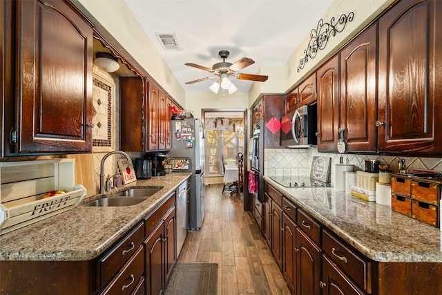 kitchen featuring hardwood / wood-style floors, sink, decorative backsplash, light stone countertops, and appliances with stainless steel finishes