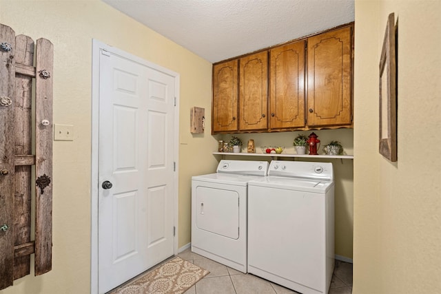 washroom featuring washer and dryer, light tile patterned floors, a textured ceiling, and cabinets