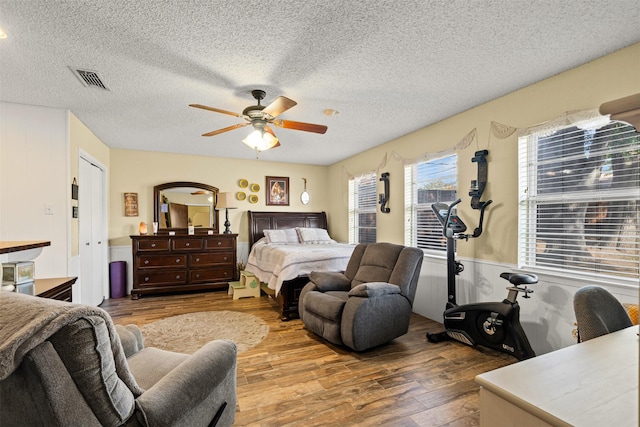 bedroom with ceiling fan, light hardwood / wood-style flooring, and a textured ceiling