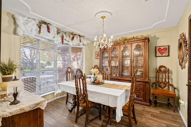 dining area with a textured ceiling, dark wood-type flooring, and an inviting chandelier