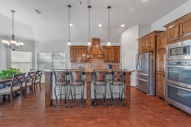 kitchen with decorative light fixtures, dark hardwood / wood-style floors, a large island with sink, and appliances with stainless steel finishes