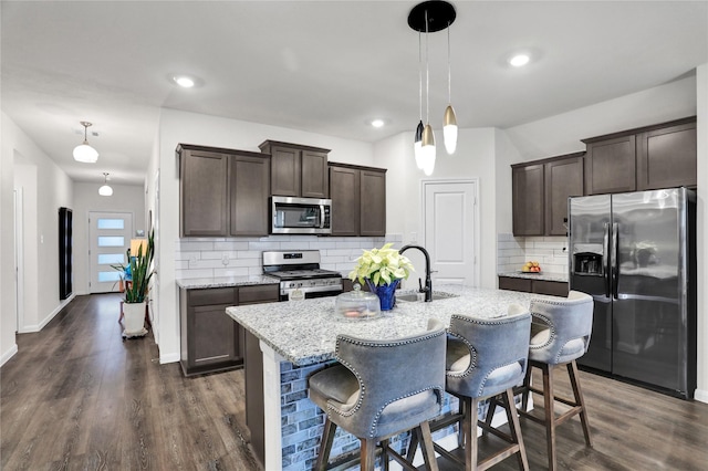 kitchen featuring pendant lighting, dark hardwood / wood-style flooring, appliances with stainless steel finishes, and tasteful backsplash