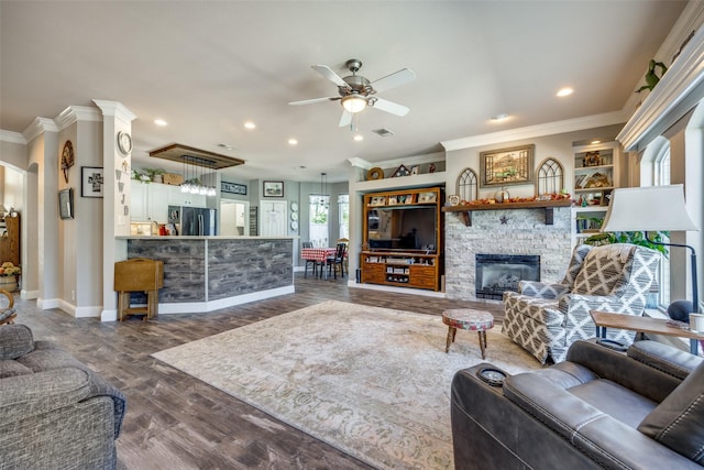 living room with a fireplace, ceiling fan, crown molding, and dark wood-type flooring