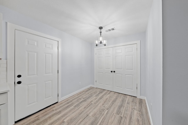 interior space featuring light hardwood / wood-style floors, a closet, and a chandelier