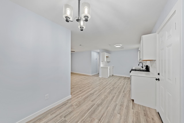 living room with light wood-type flooring, an inviting chandelier, and sink