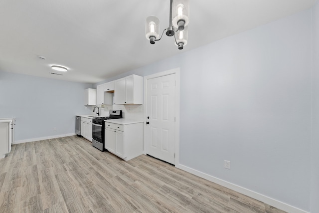 kitchen with sink, light wood-type flooring, appliances with stainless steel finishes, a notable chandelier, and white cabinetry