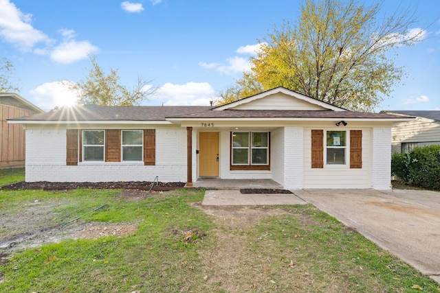 ranch-style home featuring covered porch and a front yard