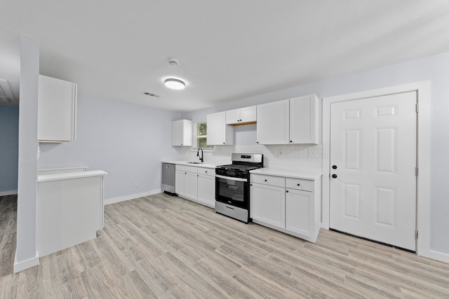 kitchen with light wood-type flooring, stainless steel appliances, white cabinetry, and sink