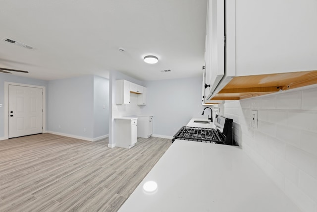 kitchen with white cabinetry, stainless steel gas stove, sink, and light wood-type flooring