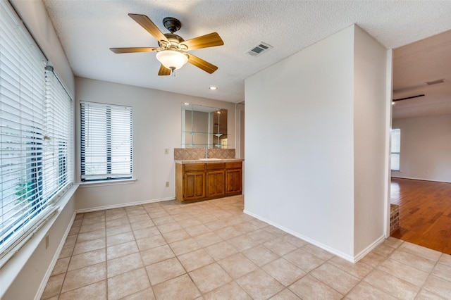 interior space with light tile patterned floors, a textured ceiling, ceiling fan, and sink