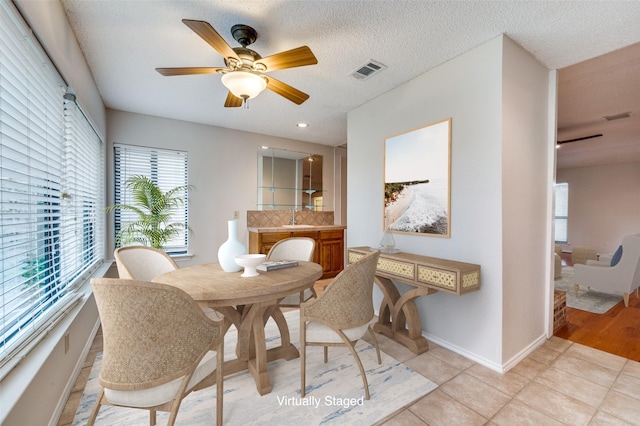 tiled dining area with a textured ceiling, ceiling fan, and sink