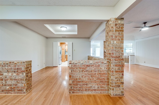 unfurnished living room with ceiling fan, light hardwood / wood-style floors, and a textured ceiling