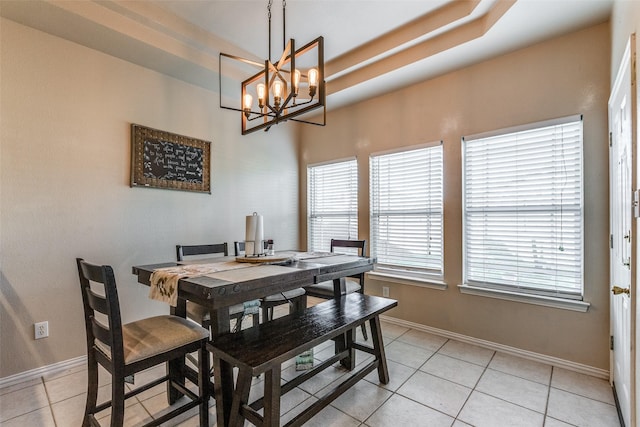 dining area with light tile patterned floors, a notable chandelier, and a tray ceiling