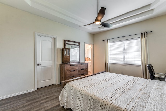 bedroom with dark wood-type flooring, ceiling fan, and a tray ceiling