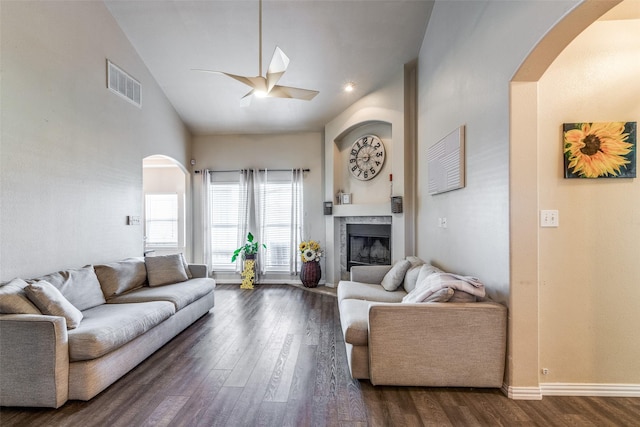 living room featuring a premium fireplace, dark wood-type flooring, and high vaulted ceiling