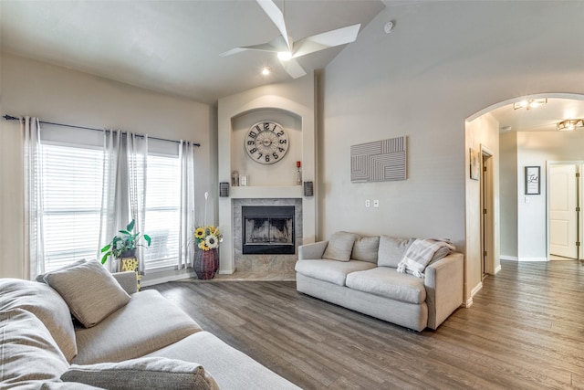 living room with a high ceiling, ceiling fan, hardwood / wood-style floors, and a high end fireplace